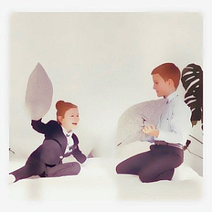 brother and sister playing with cushions on a bed